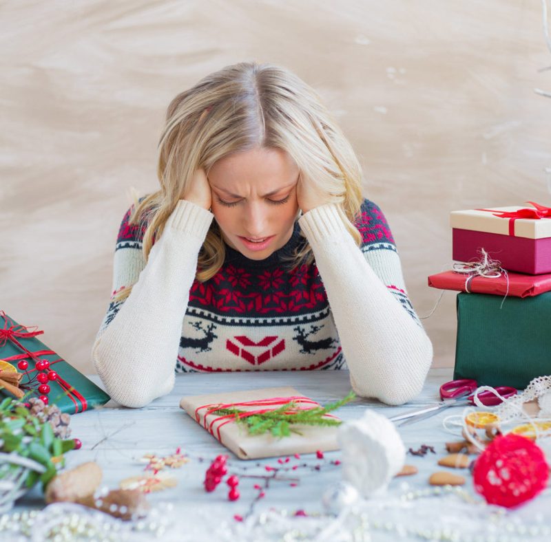 Image of woman stressed, wrapping holiday gifts.