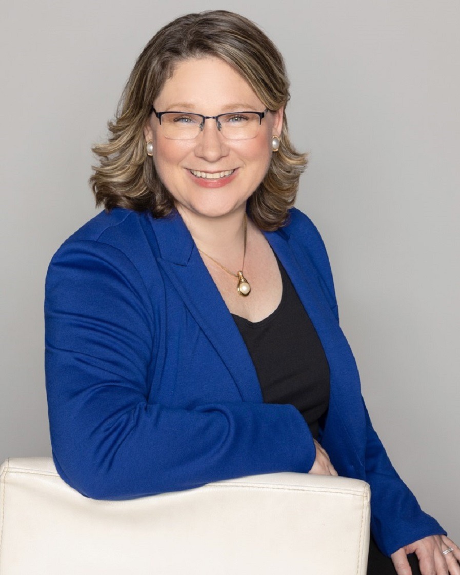 Smiling woman wearing glasses and a blue jacket