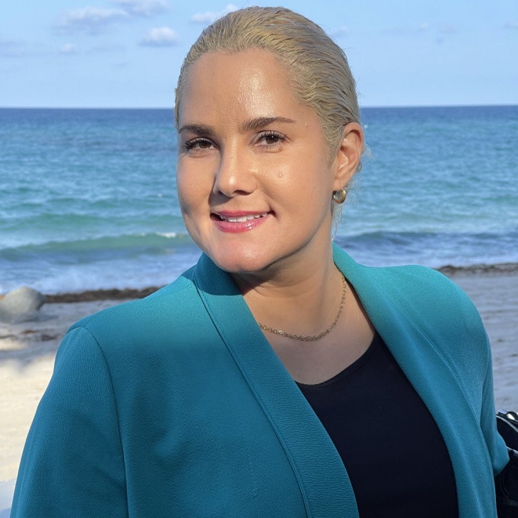 Woman with blond hair, wearing business attire, ocean background