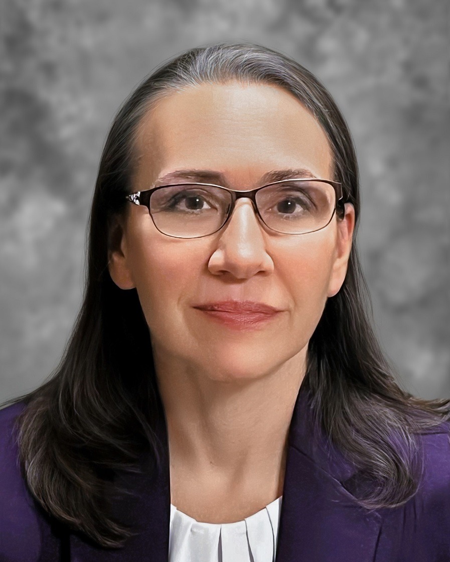 Woman with dark hair wearing business attire and glasses
